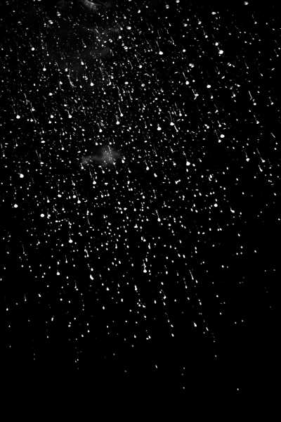 Photorealistic image of sharp-focused falling rain on black backdrop
