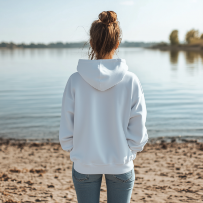 Young Woman Standing on Beach in White Hoodie