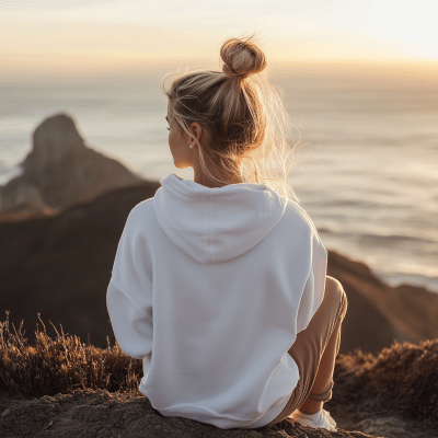 Blonde girl on cliff at sunset